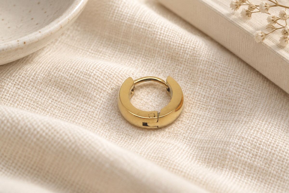 A single gold-toned hoop earring with a flat horseshoe front face, thin curved rear bridge