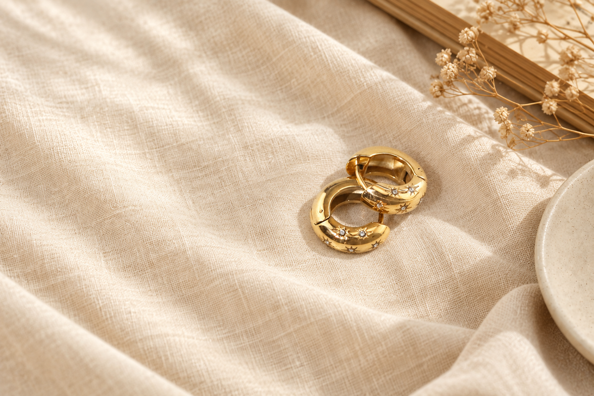 Star-detail gold hoops resting on cream linen in soft natural light