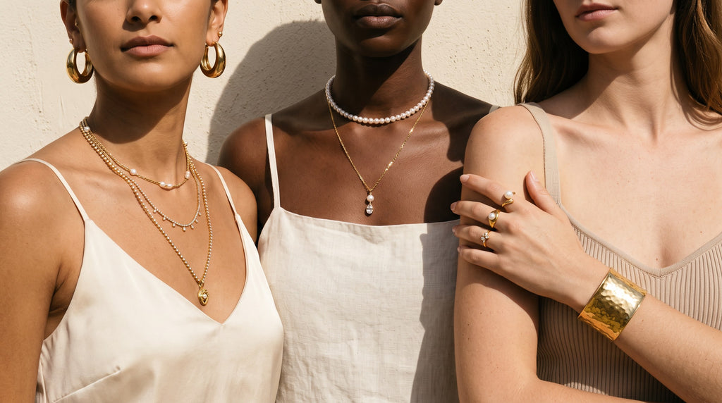 Three women wearing complete Stylr gold jewelry sets — layered necklaces, hoops, rings and a cuff