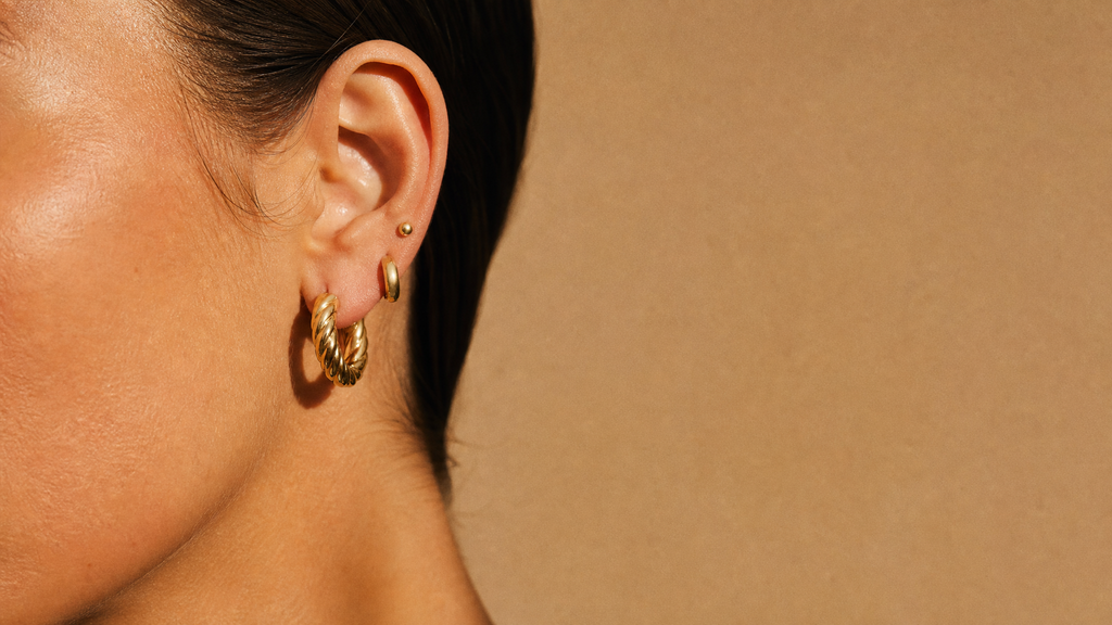 A stack of gold hoops and studs worn on one ear