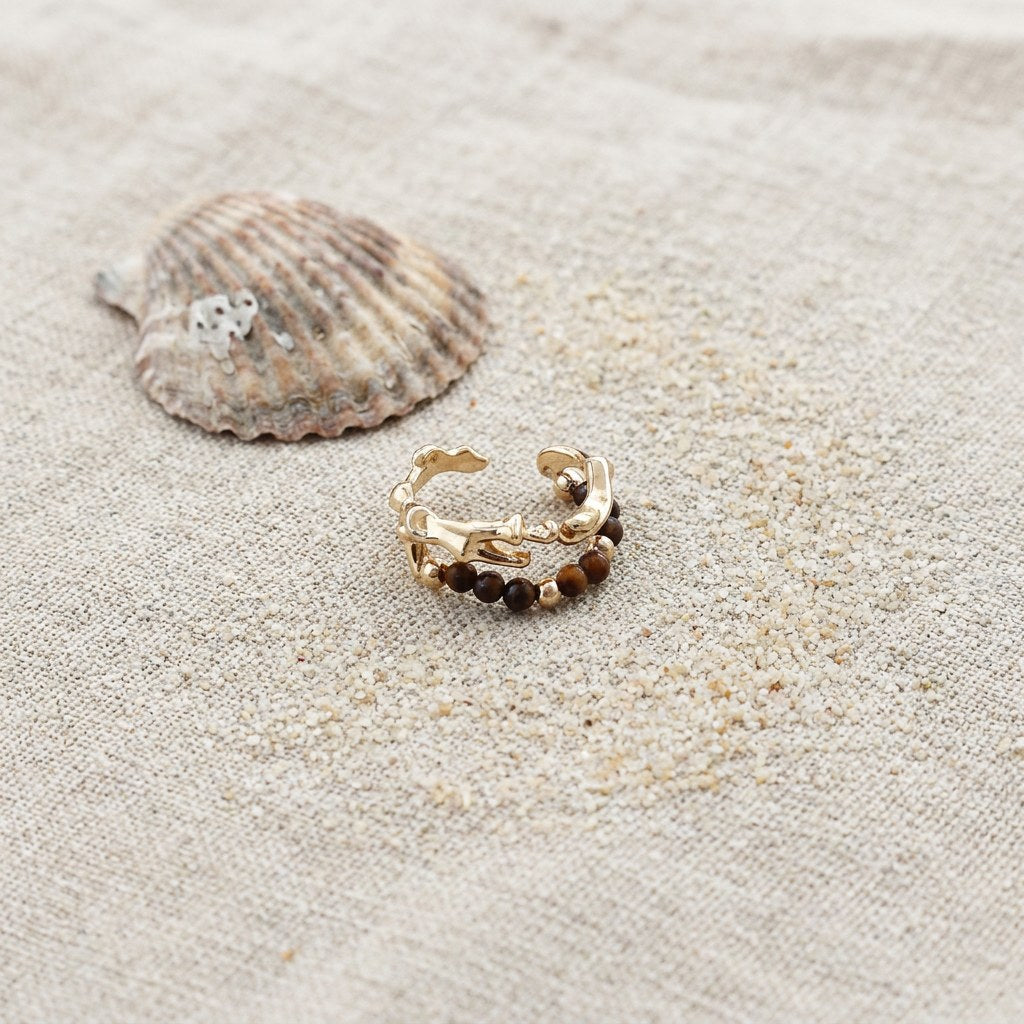 Aria Tigers Eye Beaded Ring on raw linen beside a scallop shell and a scatter of fine sand