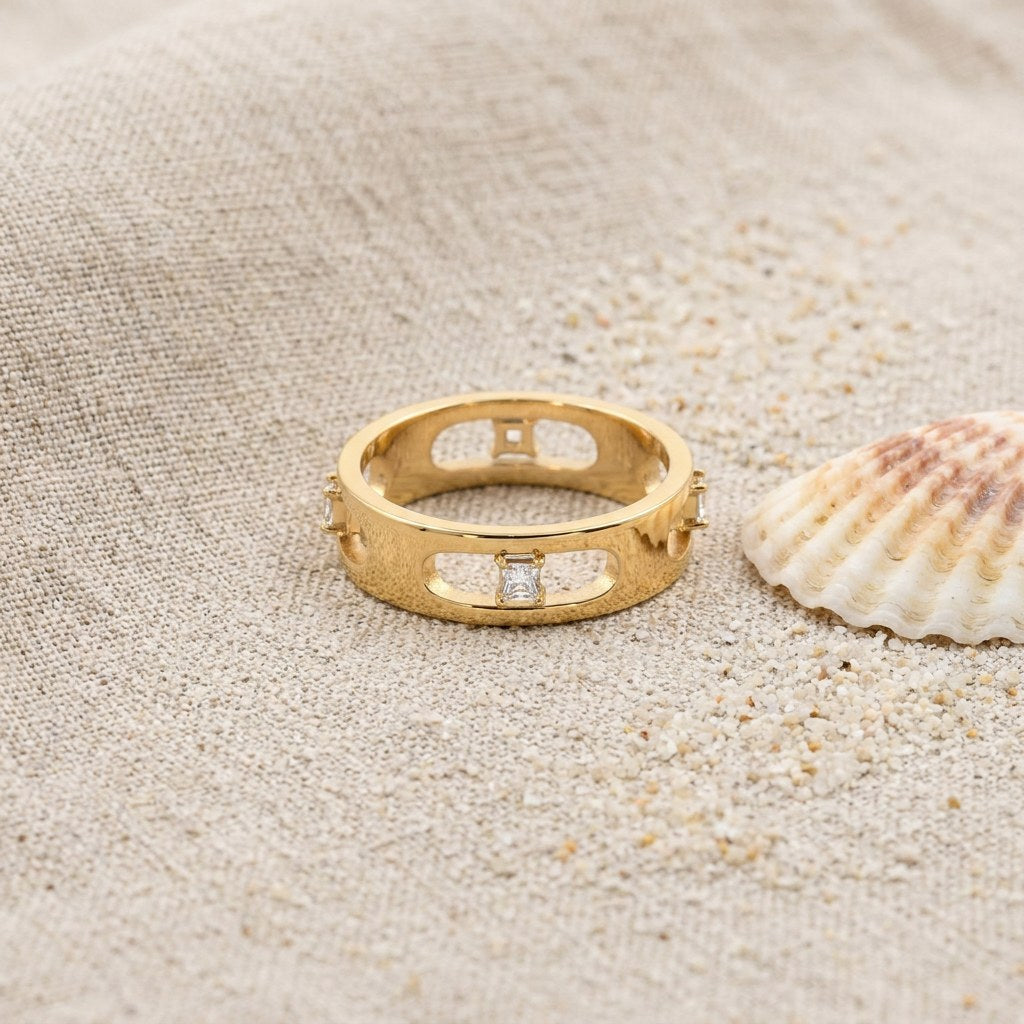 Astra Eternity Ring on raw linen beside a scallop shell and a scatter of fine sand
