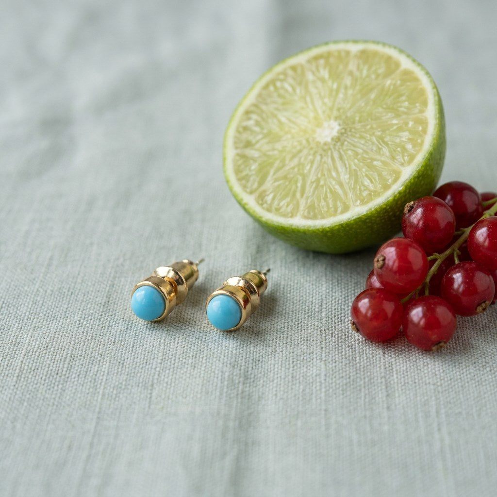 Blue Agate Stud Earrings for Women on pale grey-green linen beside a halved lime and red currants