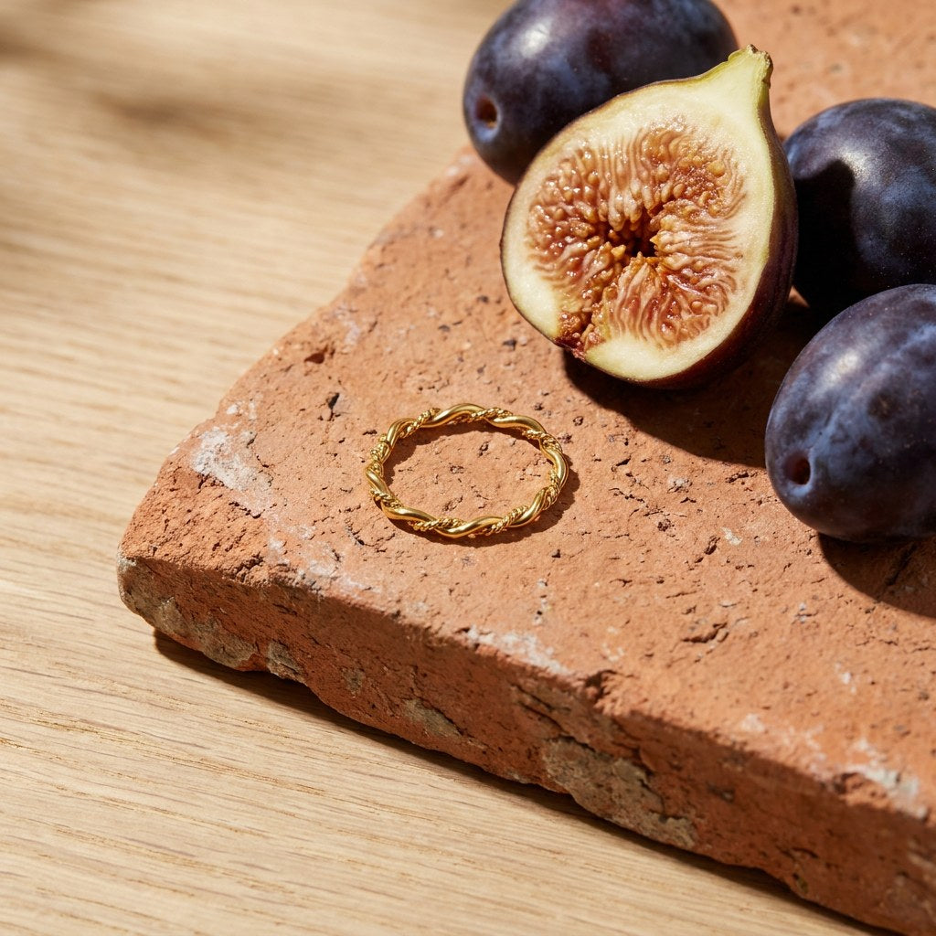 Dainty Rope Twist Ring on a weathered terracotta tile with a cut fig and dark plums