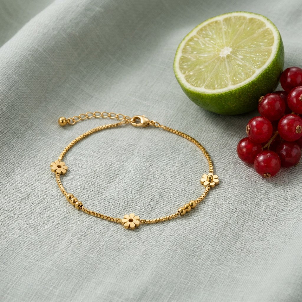 Daisy Chain Anklet on pale grey-green linen beside a halved lime and red currants