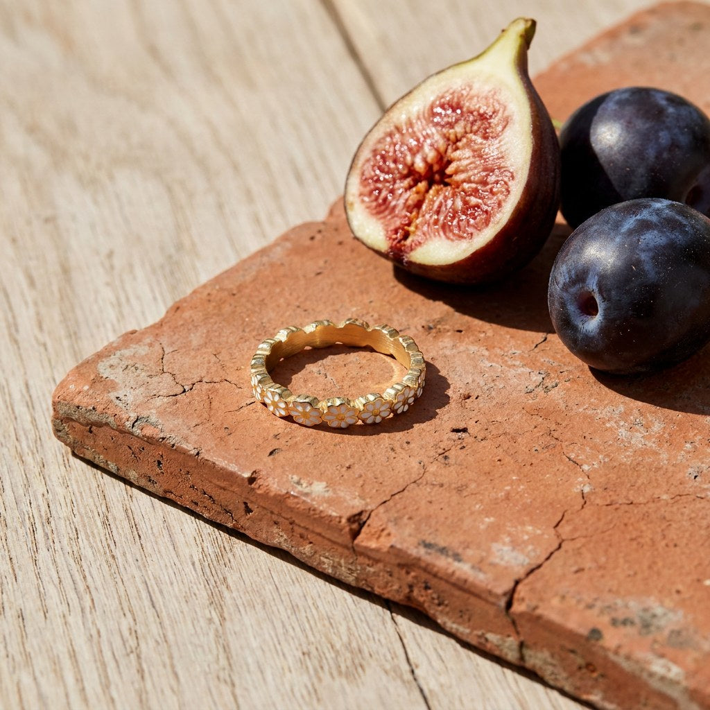 Daisy Flower Band Ring on a weathered terracotta tile with a cut fig and dark plums
