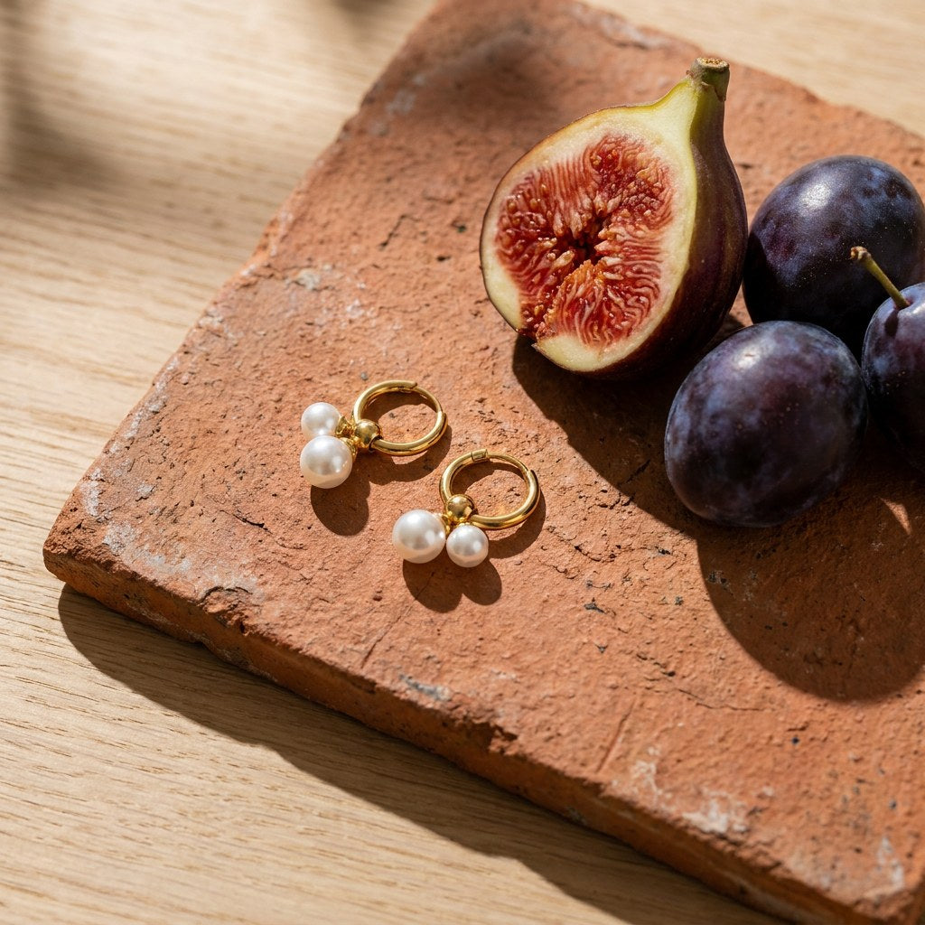 Double Pearl Hoop Earrings on a weathered terracotta tile with a cut fig and dark plums