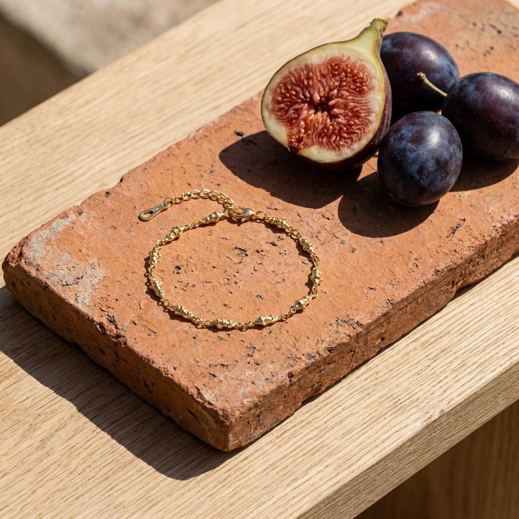 Fish Anklet on a weathered terracotta tile with a cut fig and dark plums