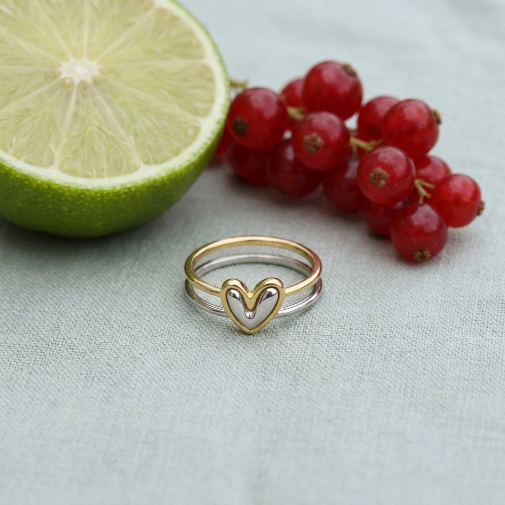 Heart to Heart Ring Set on pale grey-green linen beside a halved lime and red currants