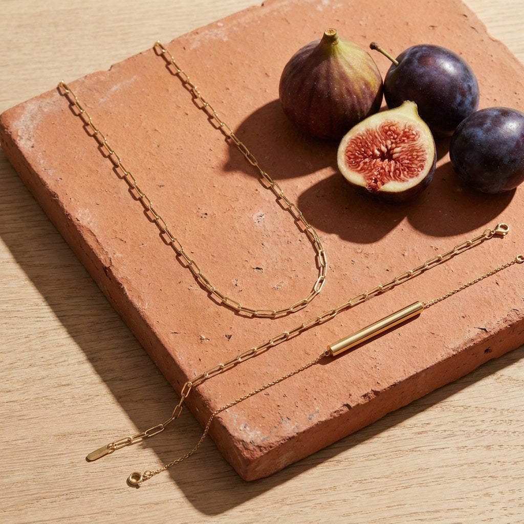 Kiva Chain Bracelet on a weathered terracotta tile with a cut fig and dark plums
