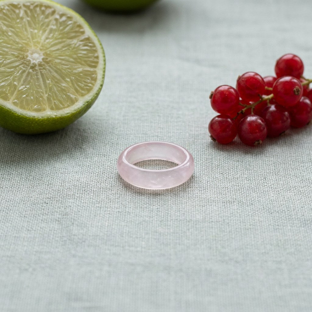 Light Pink Jade Band Ring on pale grey-green linen beside a halved lime and red currants