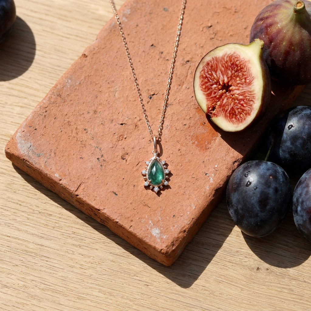 Malachite Empress Necklace: Gold Plated Pendant on a weathered terracotta tile with a cut fig and dark plums