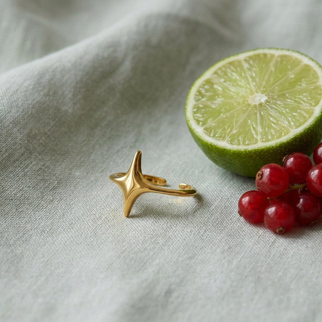 Minimalist Gold Plated Star Ring on pale grey-green linen beside a halved lime and red currants