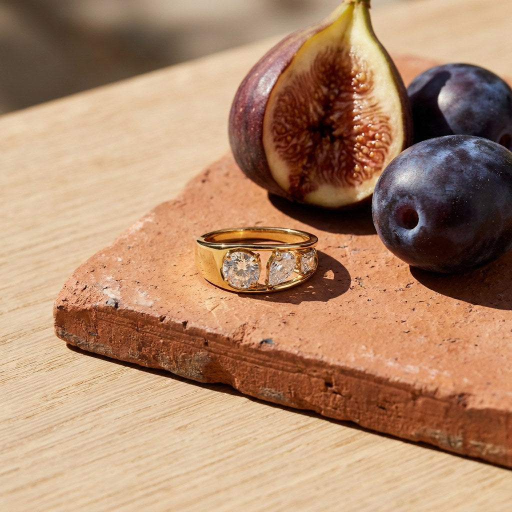 Mixed Cut Three Stone Ring on a weathered terracotta tile with a cut fig and dark plums