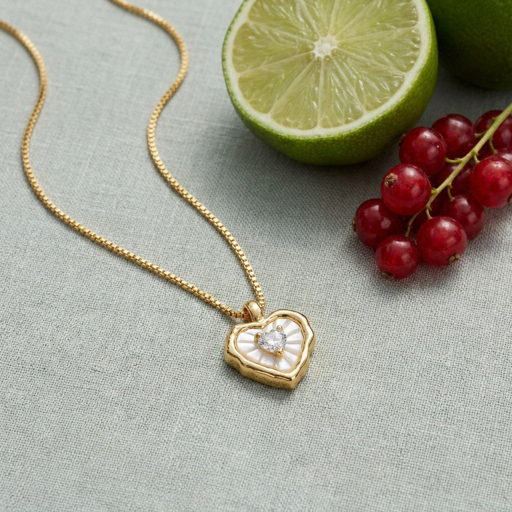 Mother of Pearl Heart Necklace on pale grey-green linen beside a halved lime and red currants