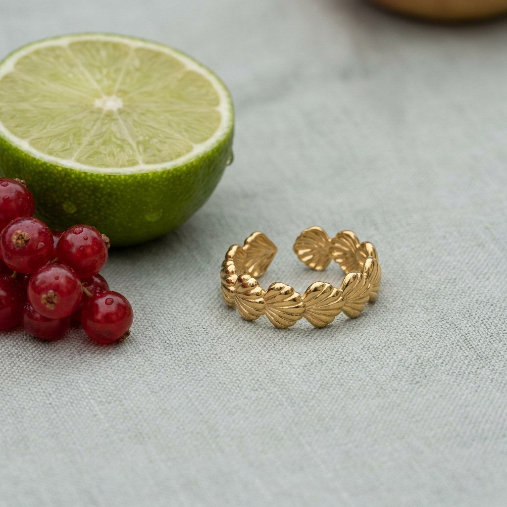 Scallop Shell Band Ring on pale grey-green linen beside a halved lime and red currants