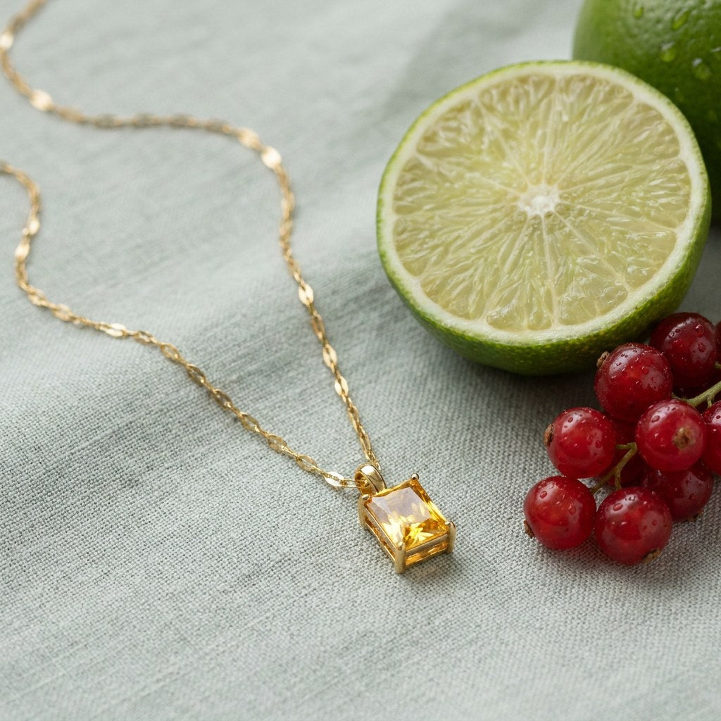 Solar Pendant Necklace on pale grey-green linen beside a halved lime and red currants