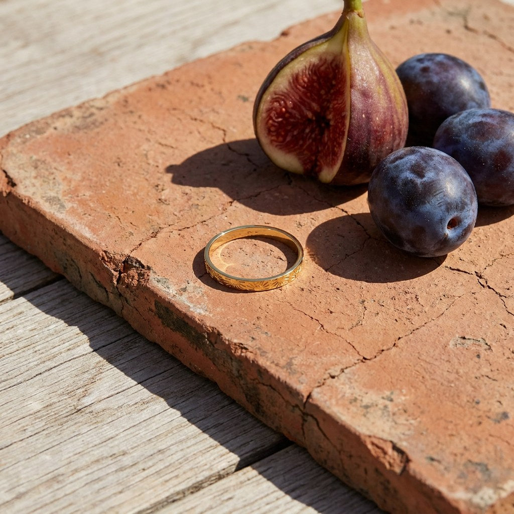 Sun Band Ring on a weathered terracotta tile with a cut fig and dark plums