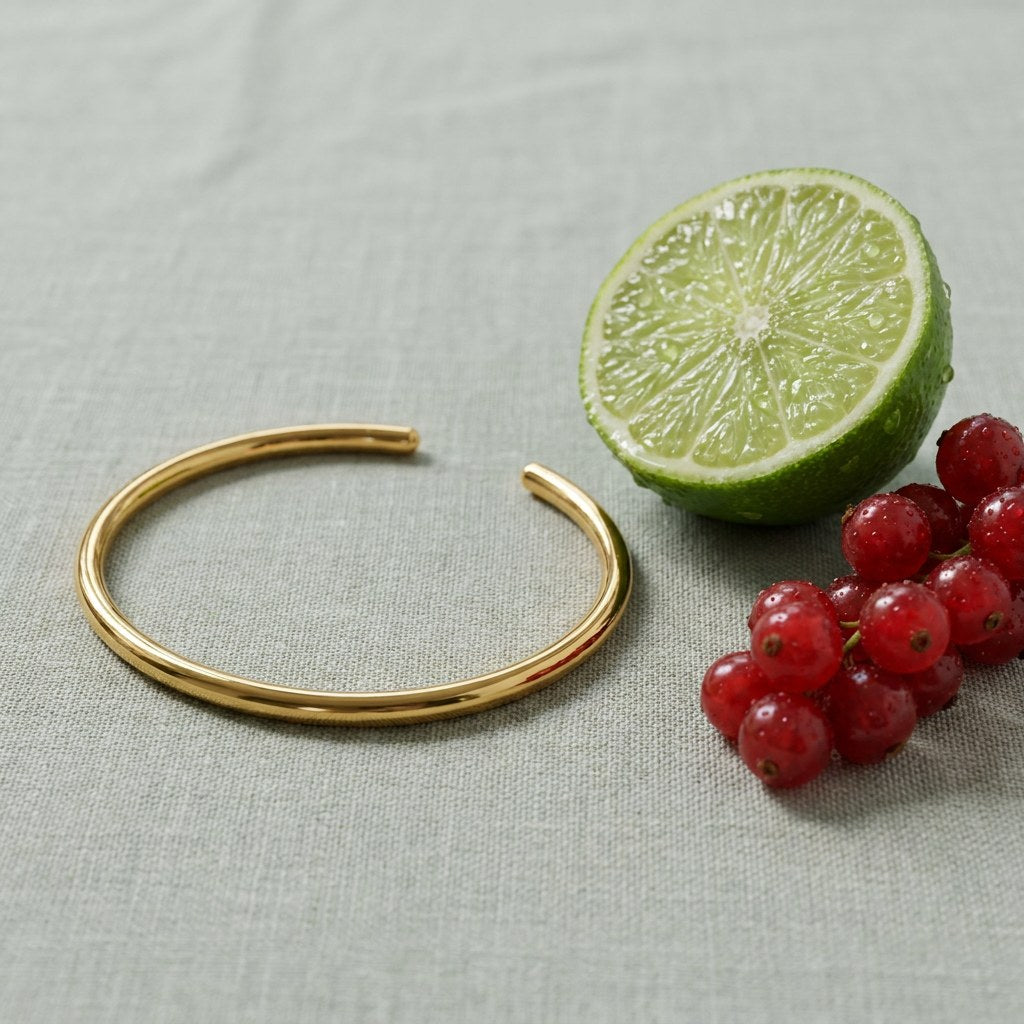 Thin Cuff Bracelet on pale grey-green linen beside a halved lime and red currants
