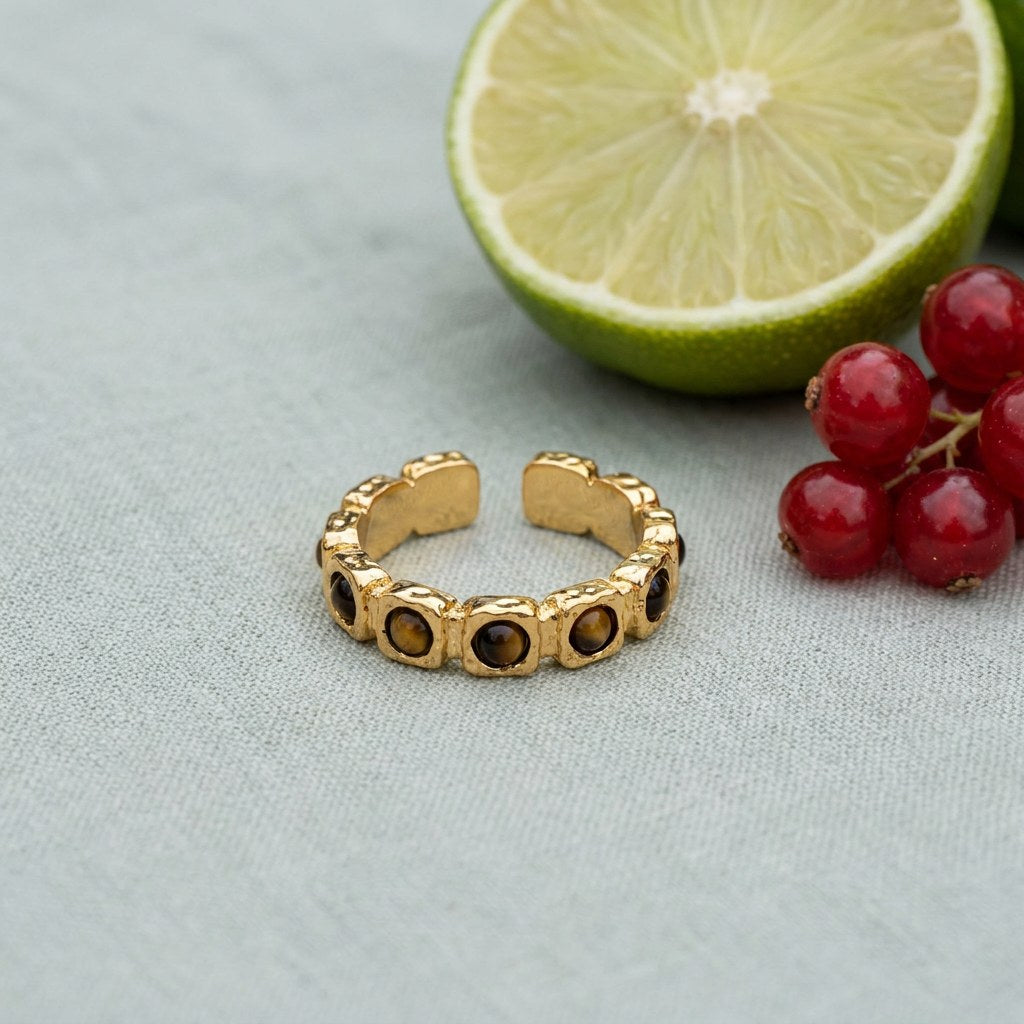 Tiger's Eye Band Ring on pale grey-green linen beside a halved lime and red currants
