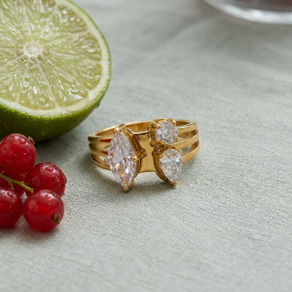 Toi et Moi Cluster Ring on pale grey-green linen beside a halved lime and red currants