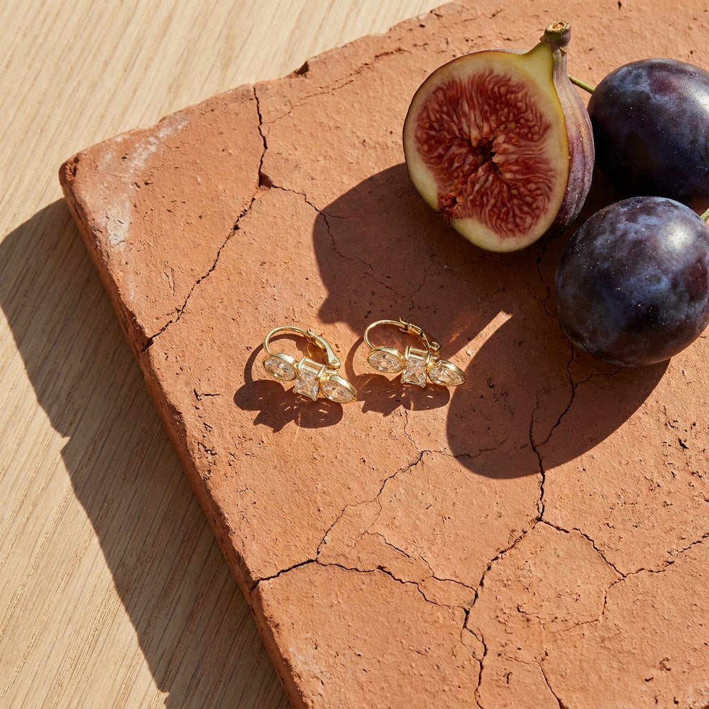 Trio Crystal Hoop Earrings on a weathered terracotta tile with a cut fig and dark plums