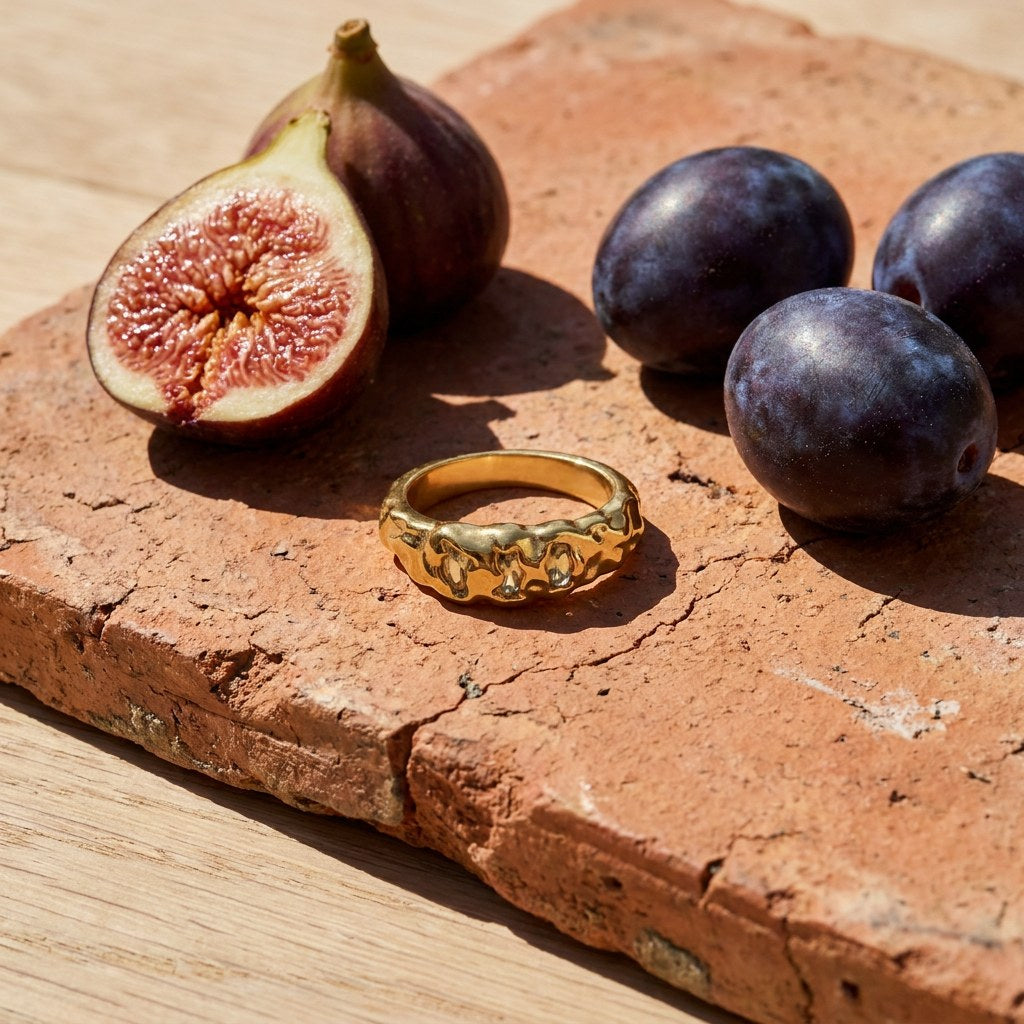 Triple Stone Hammered Ring on a weathered terracotta tile with a cut fig and dark plums