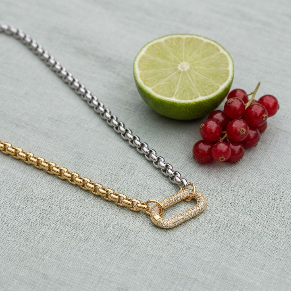 Two Tone Carabiner Necklace on pale grey-green linen beside a halved lime and red currants
