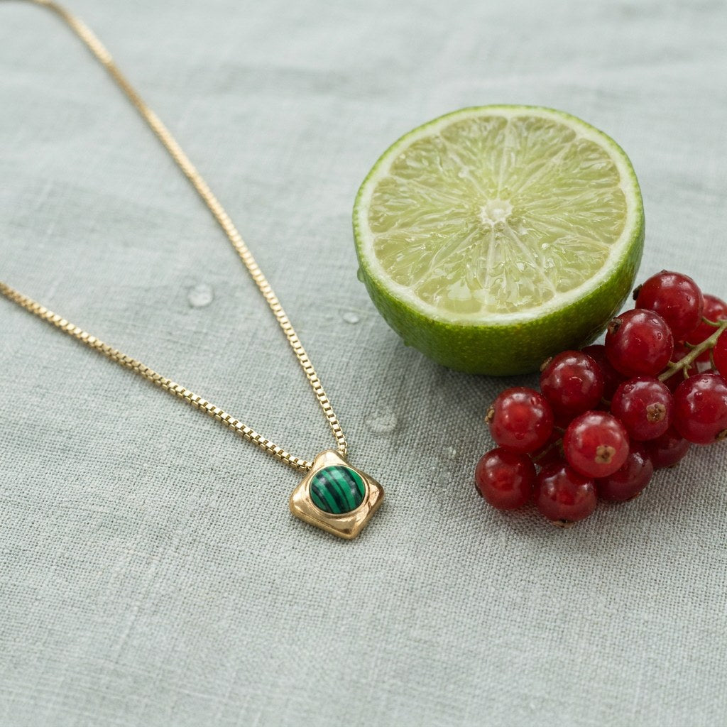 Wade Malachite Necklace on pale grey-green linen beside a halved lime and red currants
