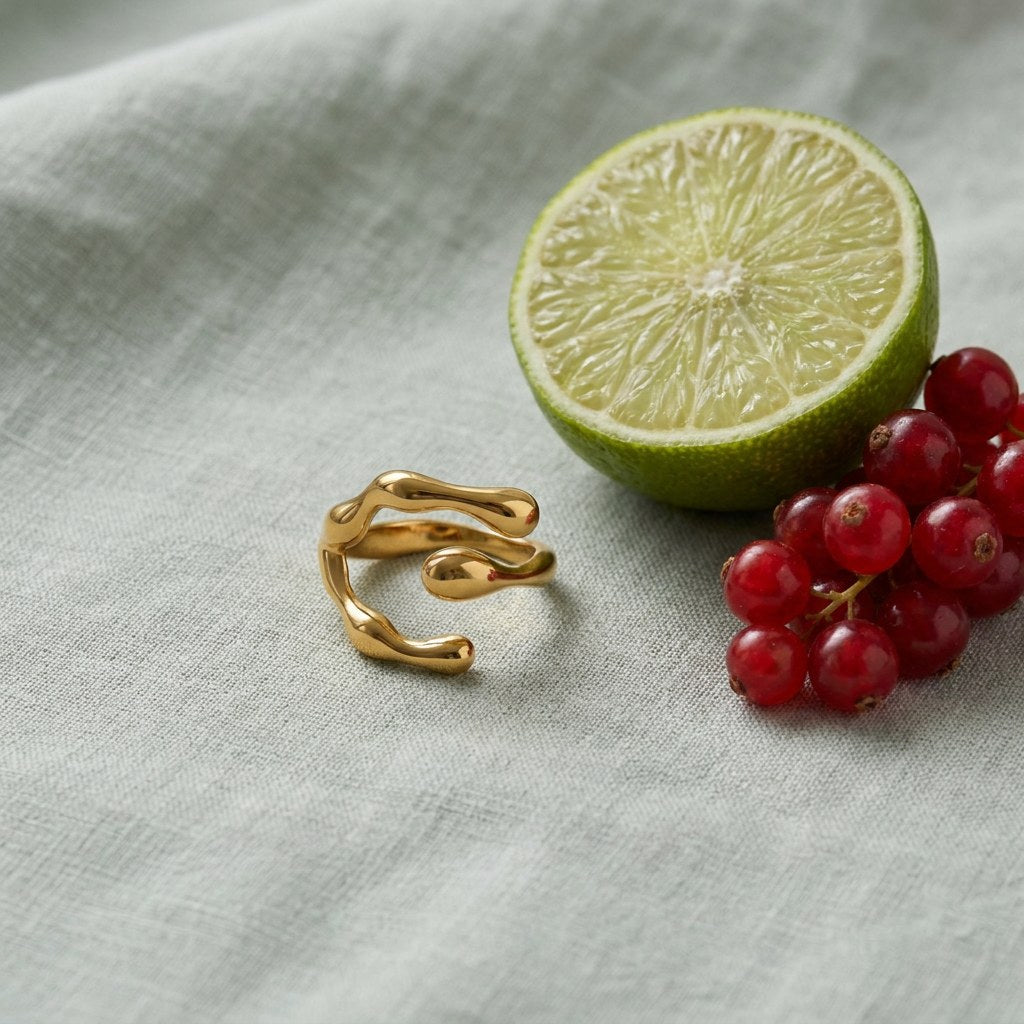 Claw Wrap Ring on pale grey-green linen beside a halved lime and red currants