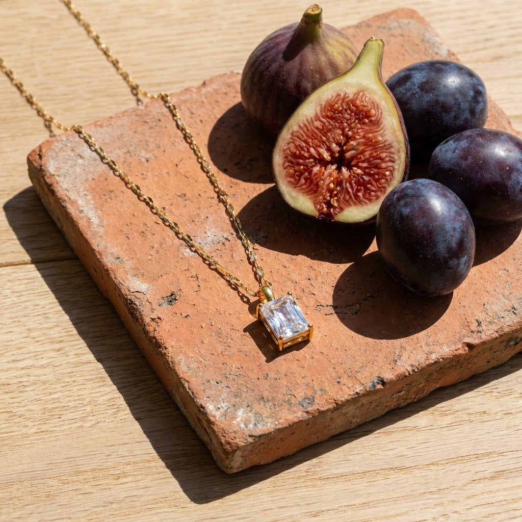 Pendant Necklace on a weathered terracotta tile with a cut fig and dark plums