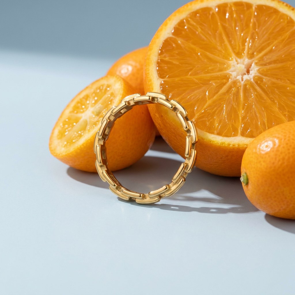 Paperclip Ring on a pale blue backdrop beside a halved orange and two kumquats