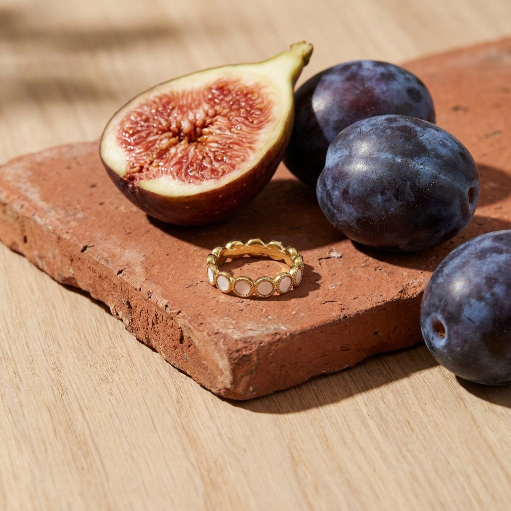 Mother of Pearl Eternity Ring on a weathered terracotta tile with a cut fig and dark plums