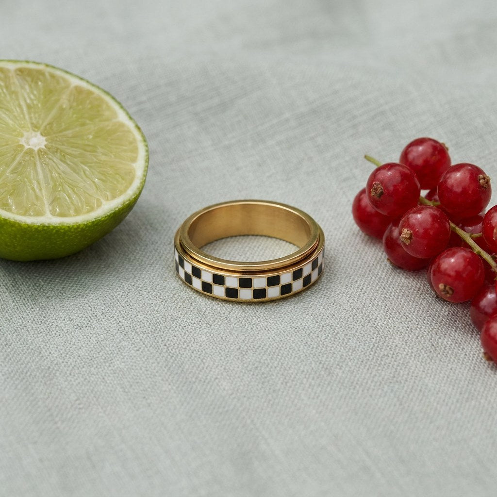 Spinner Fidget Ring on pale grey-green linen beside a halved lime and red currants