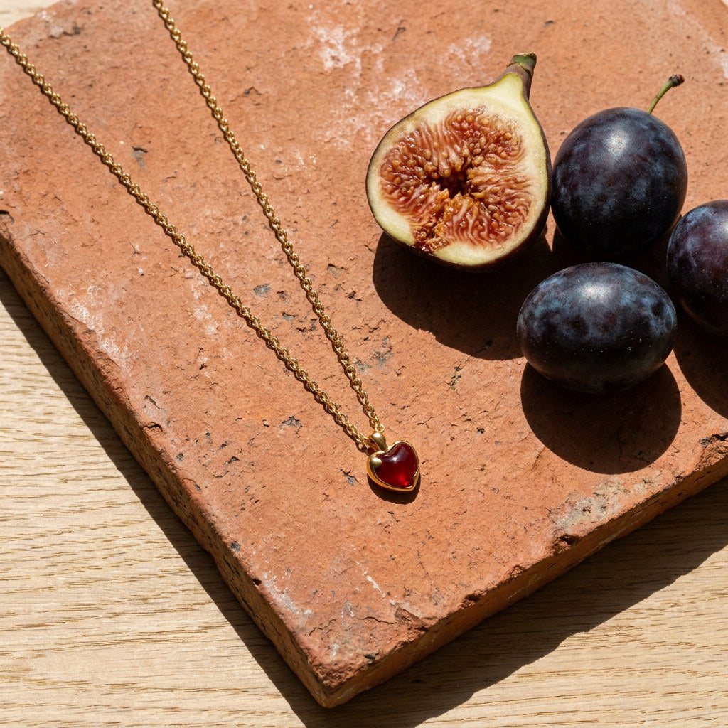 Heart Pendant Necklace on a weathered terracotta tile with a cut fig and dark plums