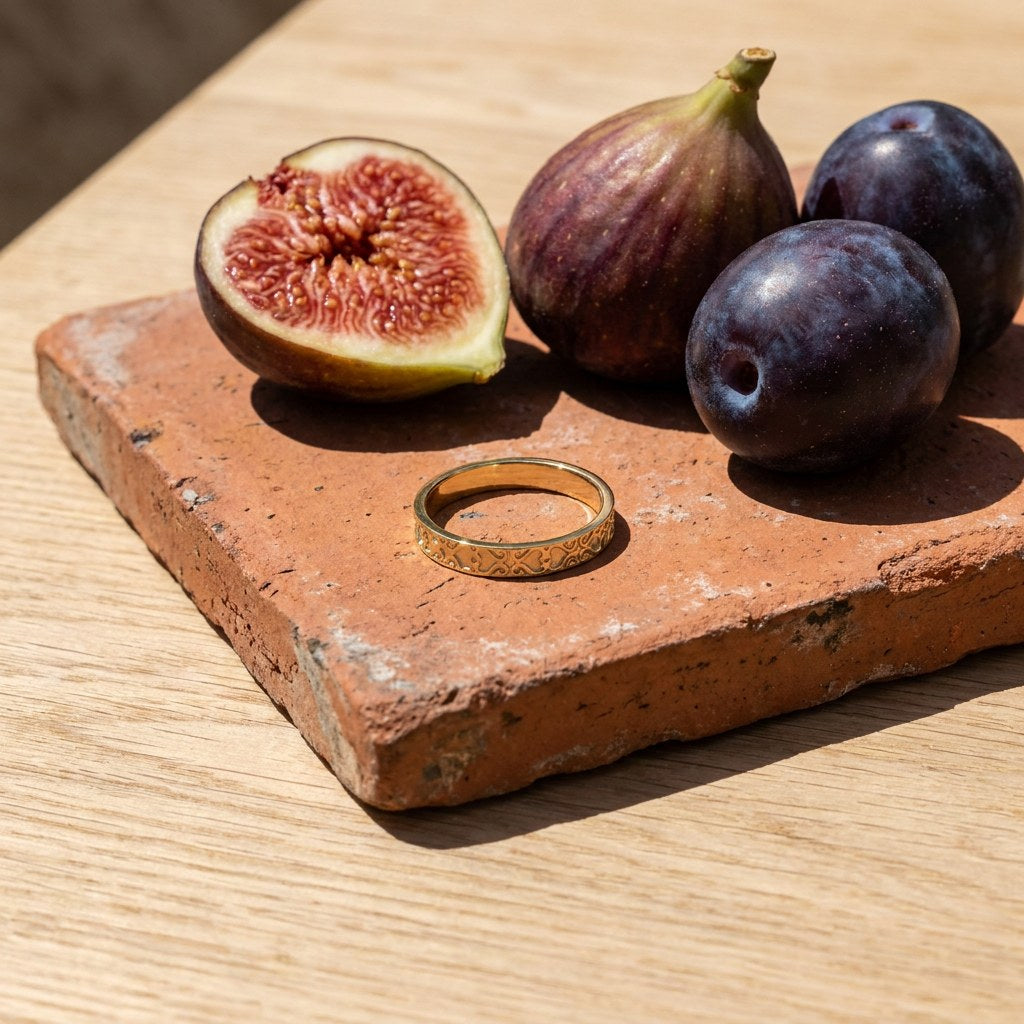 Gold Plated Band Ring on a weathered terracotta tile with a cut fig and dark plums