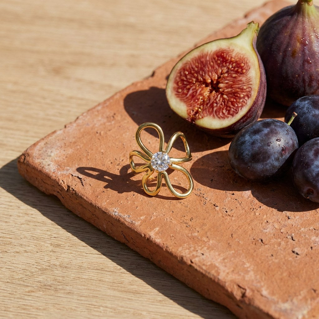 Wildflower CZ Ring on a weathered terracotta tile with a cut fig and dark plums